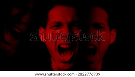 Man screaming in dramatic red lighting. Portrait of angry duality person, intense aggression, mental health disorder. Concept of fear, hysteria, instability, split mind. Two personality inner struggle