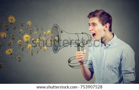 Man screaming out his ideas loud in megaphone isolated on gray wall background 