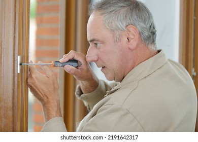 Man With Screwdriver Screwing Hinge On A Door