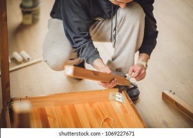 Man Screws The Legs To A Wooden Table