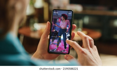 Man Scrolling Feed of Social Media Application and on Display on Smartphone. Male Resting at Home, Checking Social Network on Mobile Device. Close Up Over the Shoulder Photo. - Shutterstock ID 2190588221