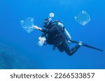 Man scuba diver cleaning plastic in the polluted sea. World ocean contaminated by plastic.