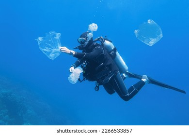 Man scuba diver cleaning plastic in the polluted sea. World ocean contaminated by plastic.
