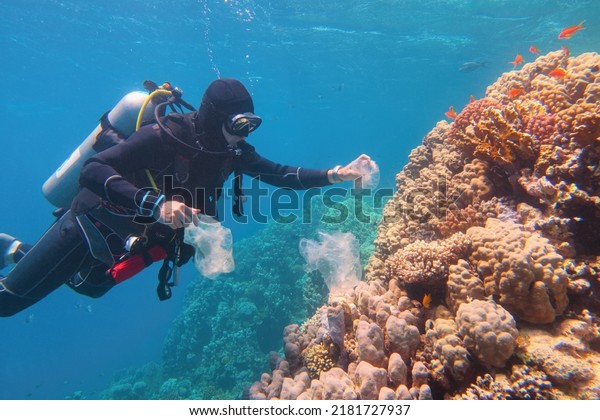 Man scuba diver cleaning plastic  from the\
tropical coral reef. World ocean contaminated by  plastic.\
Environment pollution\
concept.