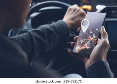 Man searching destination direction or address on GPS or navigator application via mobile smartphone inside a car in the city at night while driving car