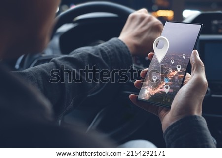 Man searching destination direction or address on GPS or navigator application via mobile smartphone inside a car in the city at night while driving car