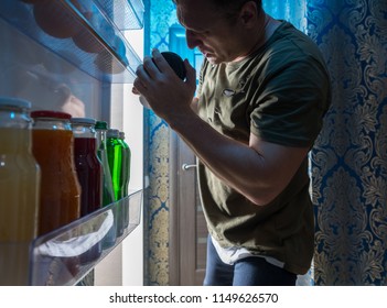 Man Searching Inside His Fridge At Night For Something To Eat And Drink Viewed From Inside The Refrigerator In An Unusual POV