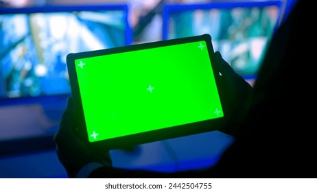 Man security guard officer in monitoring center holding tablet with chroma key green screen. Computers and big digital screen show cctv cameras footage. - Powered by Shutterstock