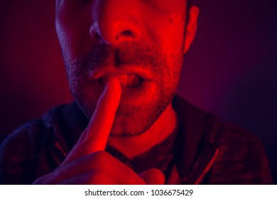 Man with seductive facial expression holding finger on mouth. Close up portrait of flirty young man with shushing gesture with his finger to his lips looking at camera. - Shutterstock ID 1036675429