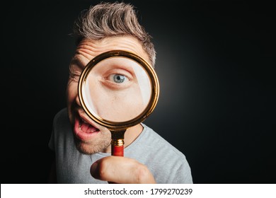 Man See Through Magnifying Glass On The Black Backgrounds. Big Man Eye