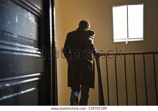 A man seen from behind is going down the\
staircase in an old parisian\
building.
