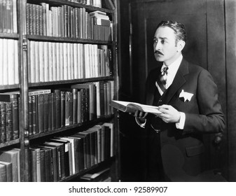 Man Selecting Books From Bookshelf In A Library