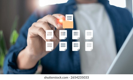 Man selecting digital folder icon among multiple document files on virtual screen, concept of paperless office, file organization, and document management system.