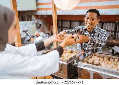 man sells various kinds of dumpling food with a cart on the side of the road - Powered by Shutterstock