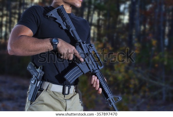 Man\
with a semi automatic rifle and handgun in the\
woods