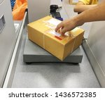 A man sendding a box on  parcel scale for delivery at counter service post office close up