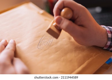 Man Sending Mail While Working In An Office, Putting Stamp On Envelope; Small Business Owner Packing Products For Delivery; Entrepreneur Getting Online Store Orders Ready For Shipping