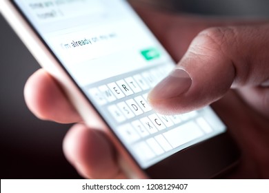 Man sending text message and sms with smartphone. Guy texting and using mobile phone late at night in dark. Communication or sexting concept. Finger typing with cellphone keyboard. Light from screen. - Shutterstock ID 1208129407