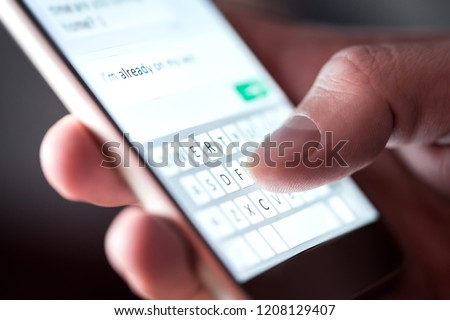 Man sending text message and sms with smartphone. Guy texting and using mobile phone late at night in dark. Communication or sexting concept. Finger typing with cellphone keyboard. Light from screen.