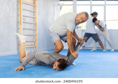 Man and senior male athletes practice Brazilian jiu Jitsu Aikido Wing chun wrestling. Training at Academy of Martial Arts martial arts hand-to-hand combat. - Powered by Shutterstock