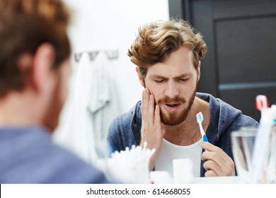 Man With Sensitive Teeth Touching His Cheek