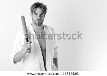 Man with serious face isolated on white background, copy space Guy poses in white kimono holding green baseball bat. Defence and sports concept. Sportsman with fit strong body gets ready to fight.