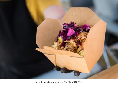 Man serving a chicken kebab with chips in a box at a Street food festival