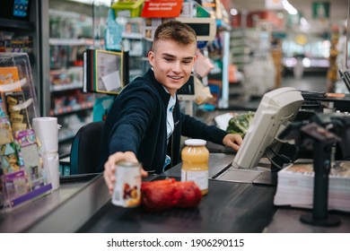 Man Serving Customers At Supermarket Checkout. Male Sales Clerk Scanning Products At Grocery Store Checkout.