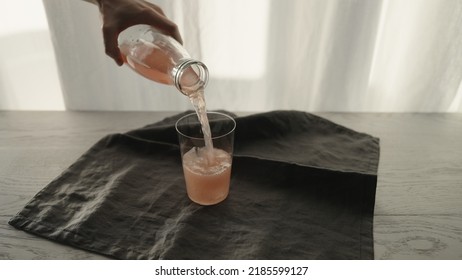 Man Serving Pink Sparkling Drink Into Tumbler Glass With Ice Chunk, Wide Photo