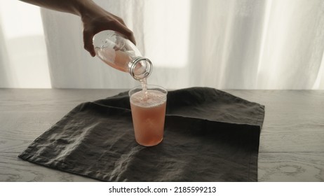 Man Serving Pink Sparkling Drink Into Tumbler Glass With Ice Chunk, Wide Photo