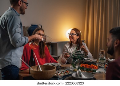 Man Serving Wine To Guests At Dinner Party