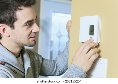 A man set the thermostat at house.