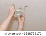 A man sets up a platform under the lamp for stretch ceiling.