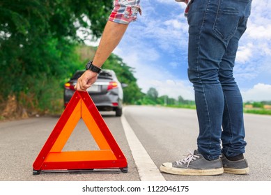 man sets the warning triangle on the country road.