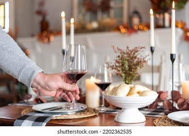 Man Setting A Glass Of Red Wine On A Holiday Dinner Table Decorated For Autumn