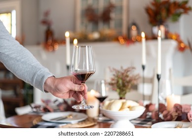 Man Setting A Glass Of Red Wine On A Thanksgiving Dinner Table