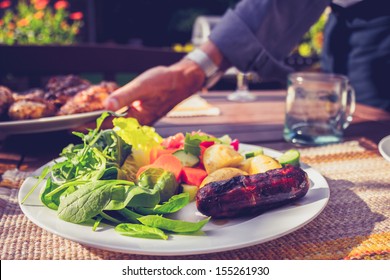 Man Setting Table At Outdoors Barbecue