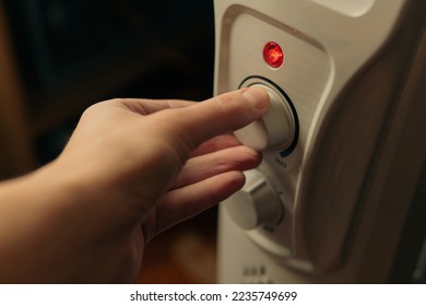 Man setting temperature on the oil electric heater on at home. Cold winter, economic crisis concept. Home heating and heat conservation. Close-up shot.