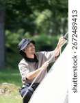 A man setting up a tent while camping in a beautiful green forest An image of solo camping, etc.