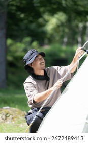 A man setting up a tent while camping in a beautiful green forest An image of solo camping, etc.