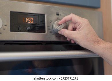 Man Setting The Timer Clock On The Oven. Turning Knob To Set The Timer.