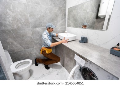 A man is setting the washbasin over the cabinet in the bathroom