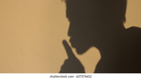 Man Shadow Shush Sign On Brown Wall