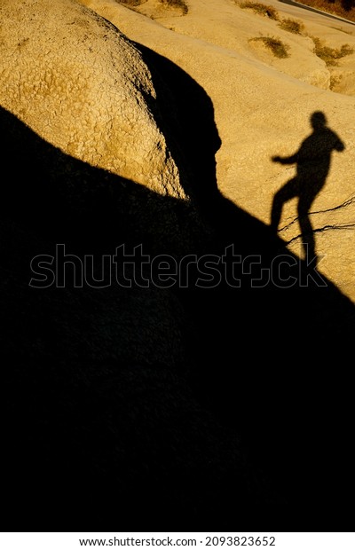 Man shadow\
silhouette projected over a dried mud ravine yellowed by the\
setting sun at Berca Mud Volcanoes\
reservation