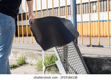 Man Shaking A Car Floor Mat On A Metal Structure On A Sunny Day. Car Cleaning