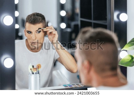 Man shaping his eyebrows while doing makeup for a show