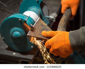 Man Sharpening An Ax Blade On A Grinder