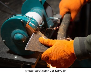 Man Sharpening An Ax Blade On A Grinder