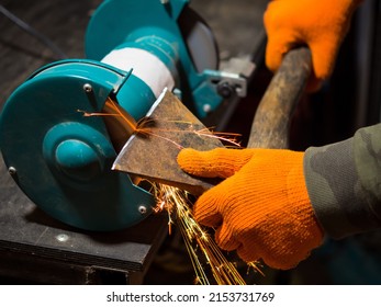 man sharpening an ax blade on a grinder - Powered by Shutterstock