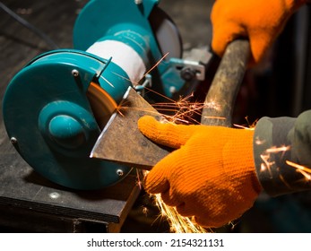 Man Sharpening An Ax Blade On A Grinder